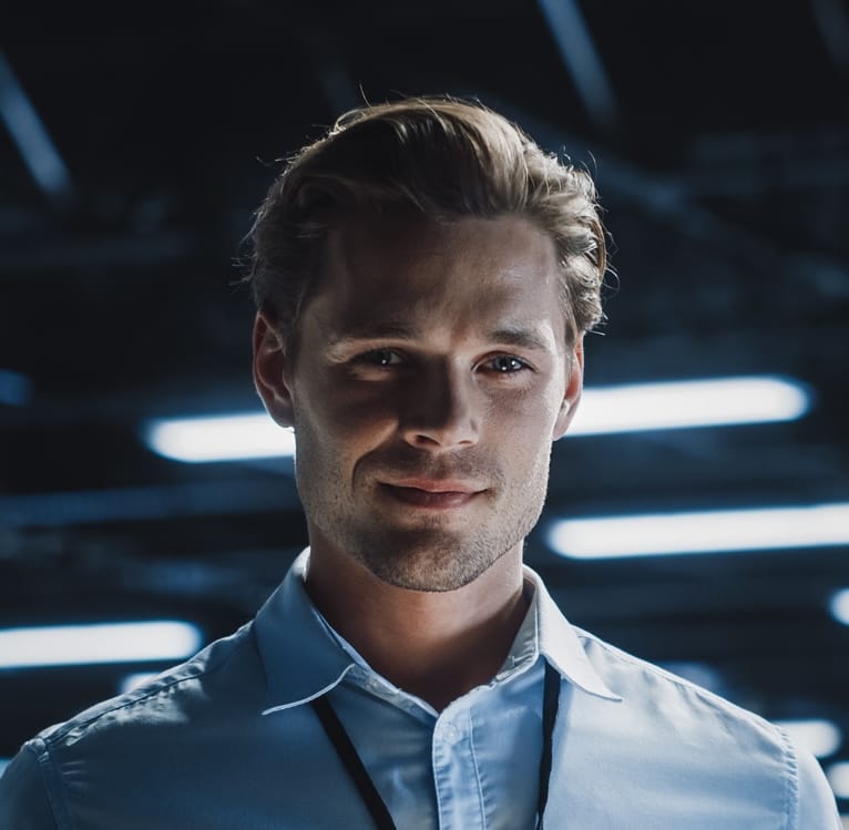 Portrait of handsome smiling it specialist using tablet computer in data center, looking at camera. succesful male e business engineer working in big server farm cloud computing facility.